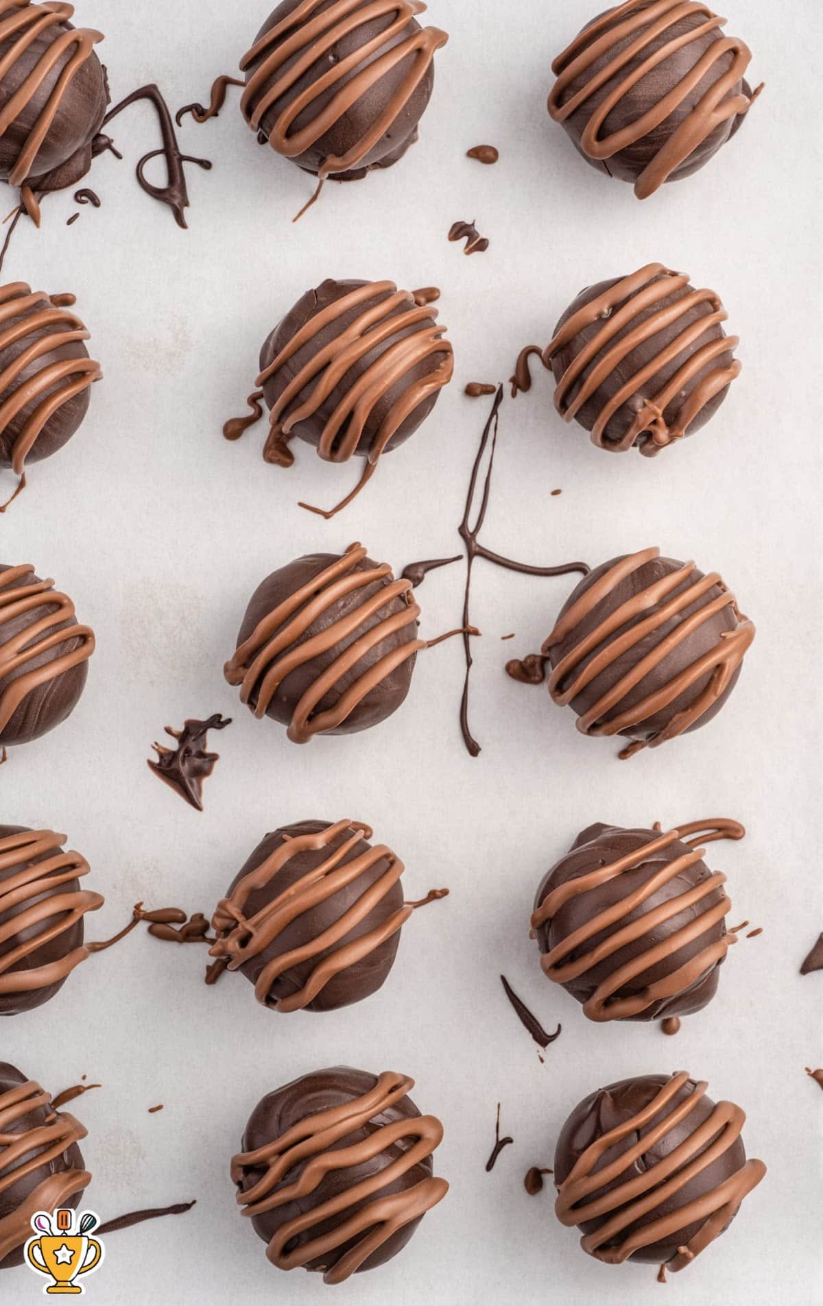 milk chocolate drizzled over the top of each cookie dough truffle on a baking sheet