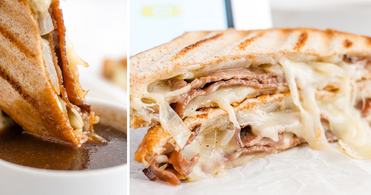 close up shot of roast beef panini with au jus cut in half and stacked on top of each other"