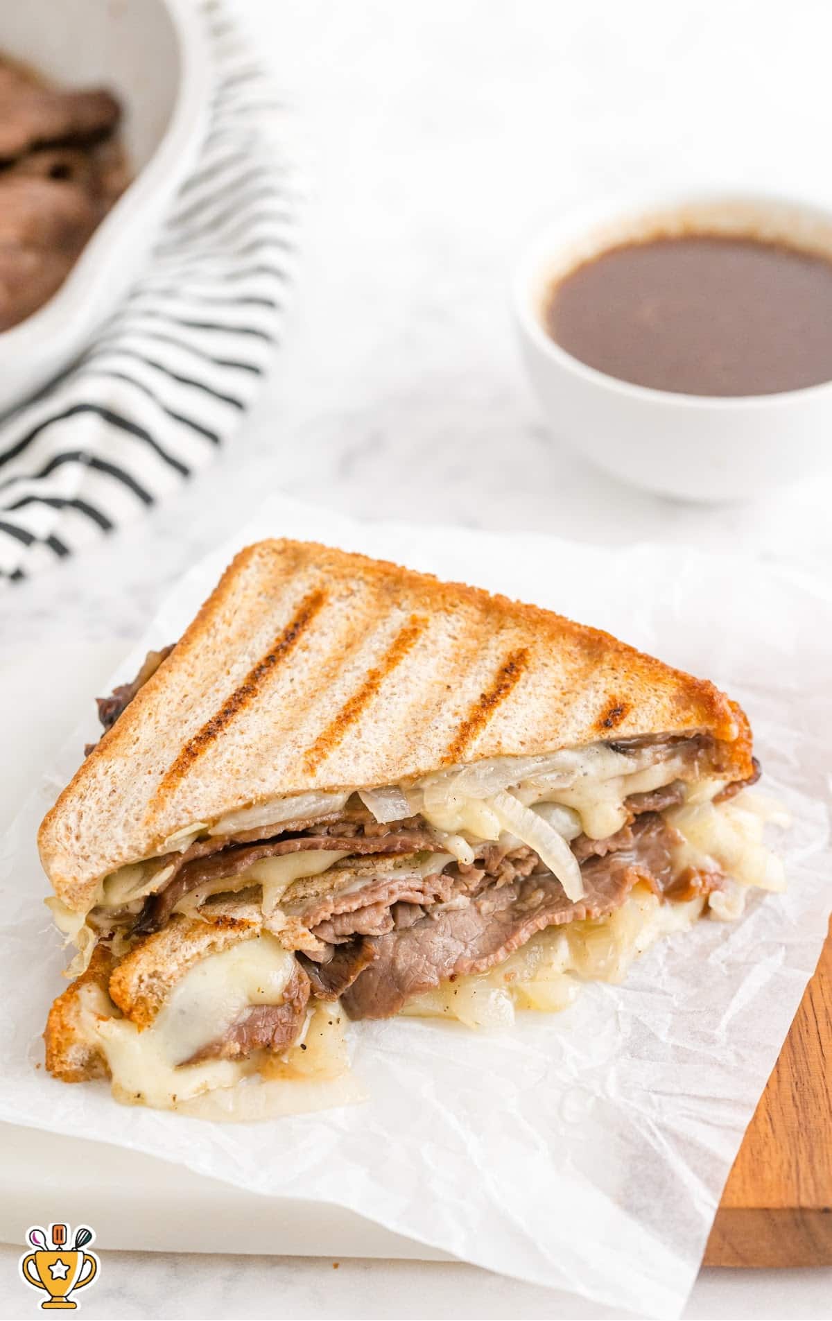 close up shot of roast beef panini with au jus cut in half and stacked on top of each other