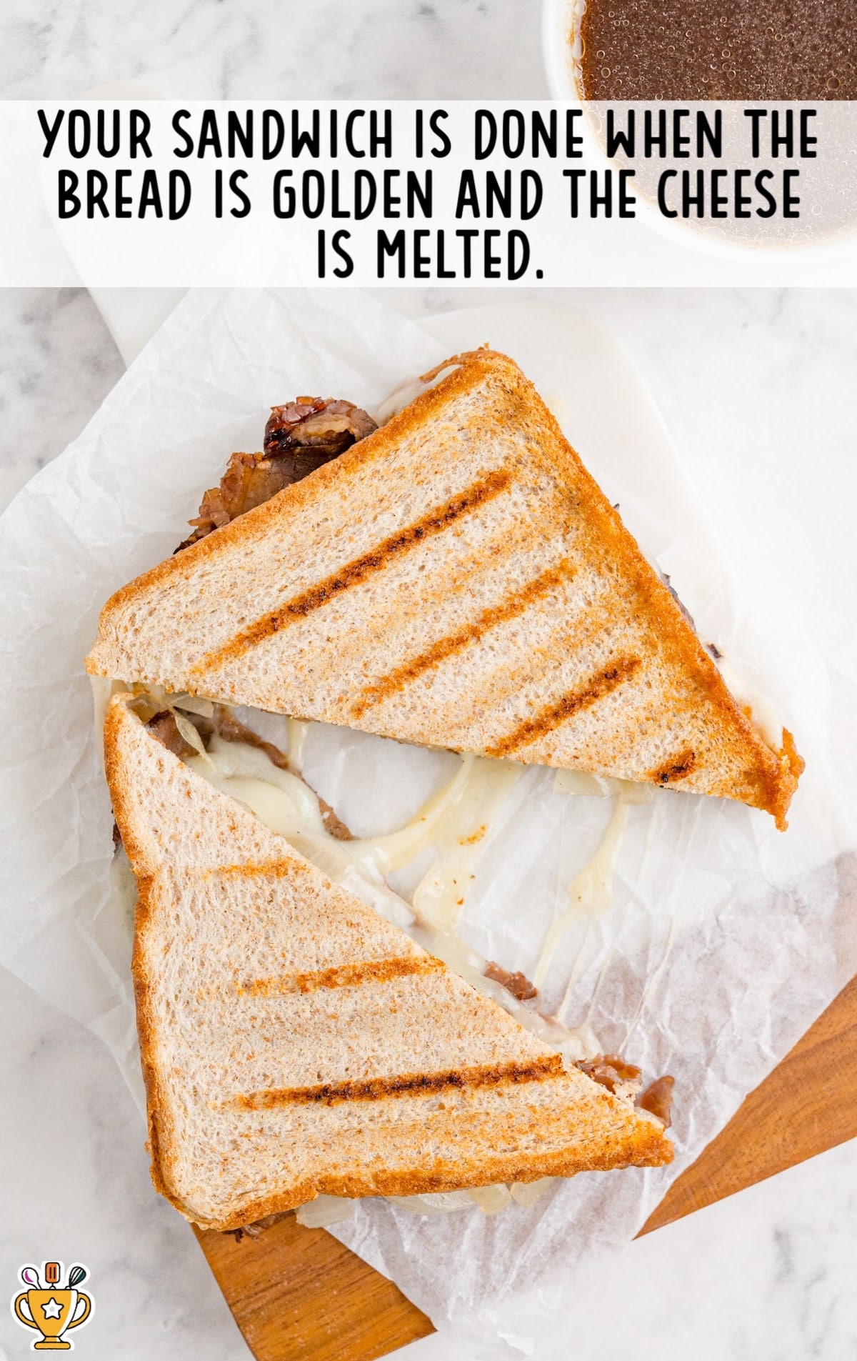 close up shot of a slice of roast beef panini with au jus being dipped into a roast beef sauce