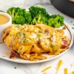 A dinner plate of alice springs chicken with sauce and broccoli.