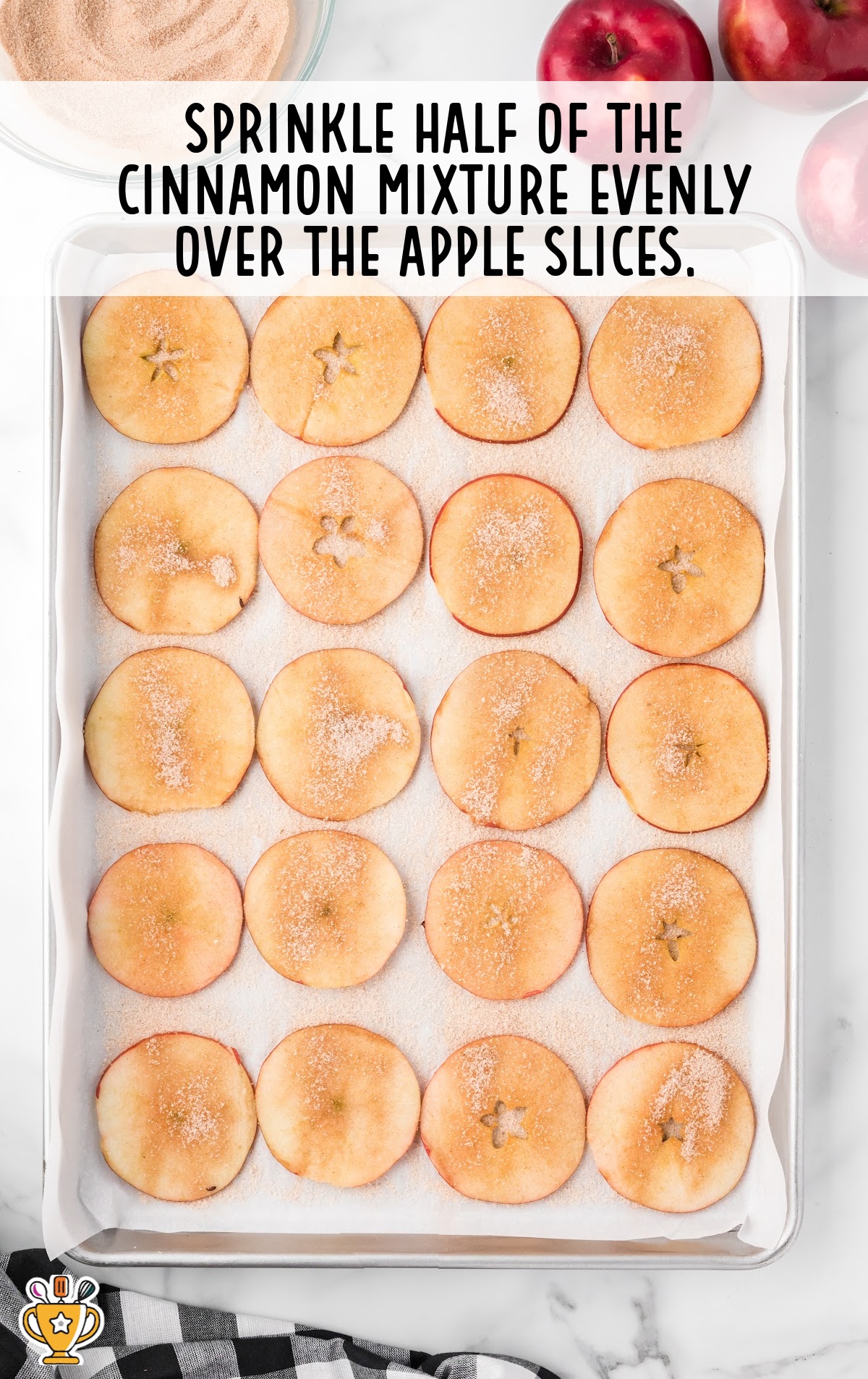 cinnamon sugar sprinkles over the apple slices on the baking sheet