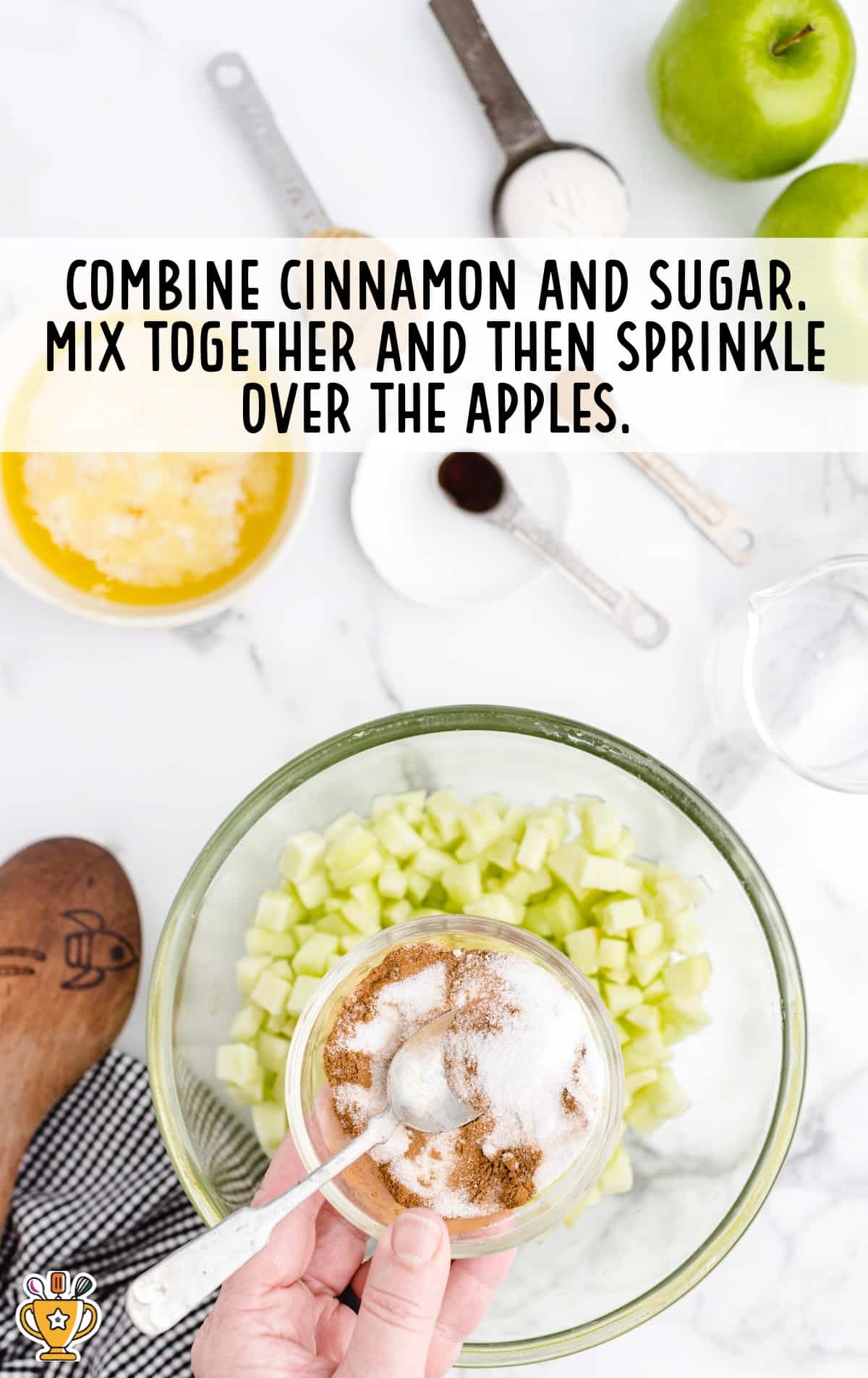 Apples in a bowl beside a bowl of cinnamon sugar with a spoon in it.