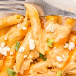 a serving of buffalo chicken pasta on a white plate with a fork.