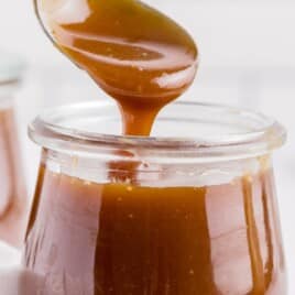 a spoon with a scoop of caramel lifted out of a jar.