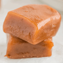 two homemade caramel squares stacked on each other showing chewy texture and soft edges