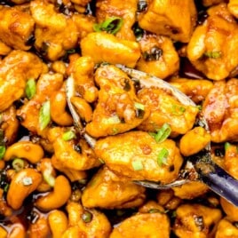 Close up of a scoop of cashew chicken in a serving spoon.