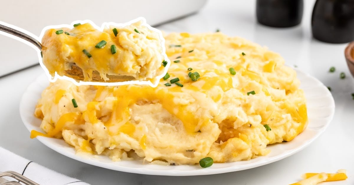 A plate of Cheesy Mashed Potatoes with a spoon holding some