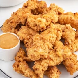 a serving plate of cooked chicken tenders with dipping sauce