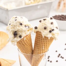 two waffle cones in a dish with scoops of chocolate chip ice cream on top