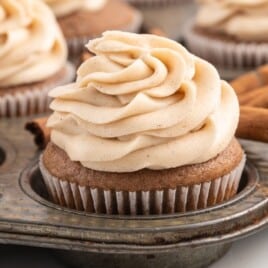 A metal cupcake tin filled with cupcakes topped with frosting.