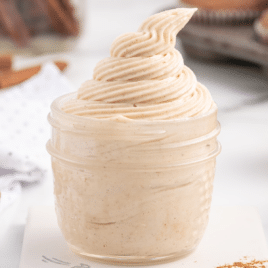 a close up of a clear jar of cinnamon cream cheese frosting