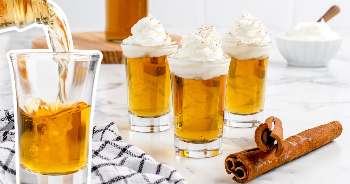 Cinnamon Roll Fireball Shot in three glasses with cinnamon barks on the side and a bottle of whiskey pouring into a glass