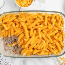 A clear glass baking dish with a scoop of casserole out of it