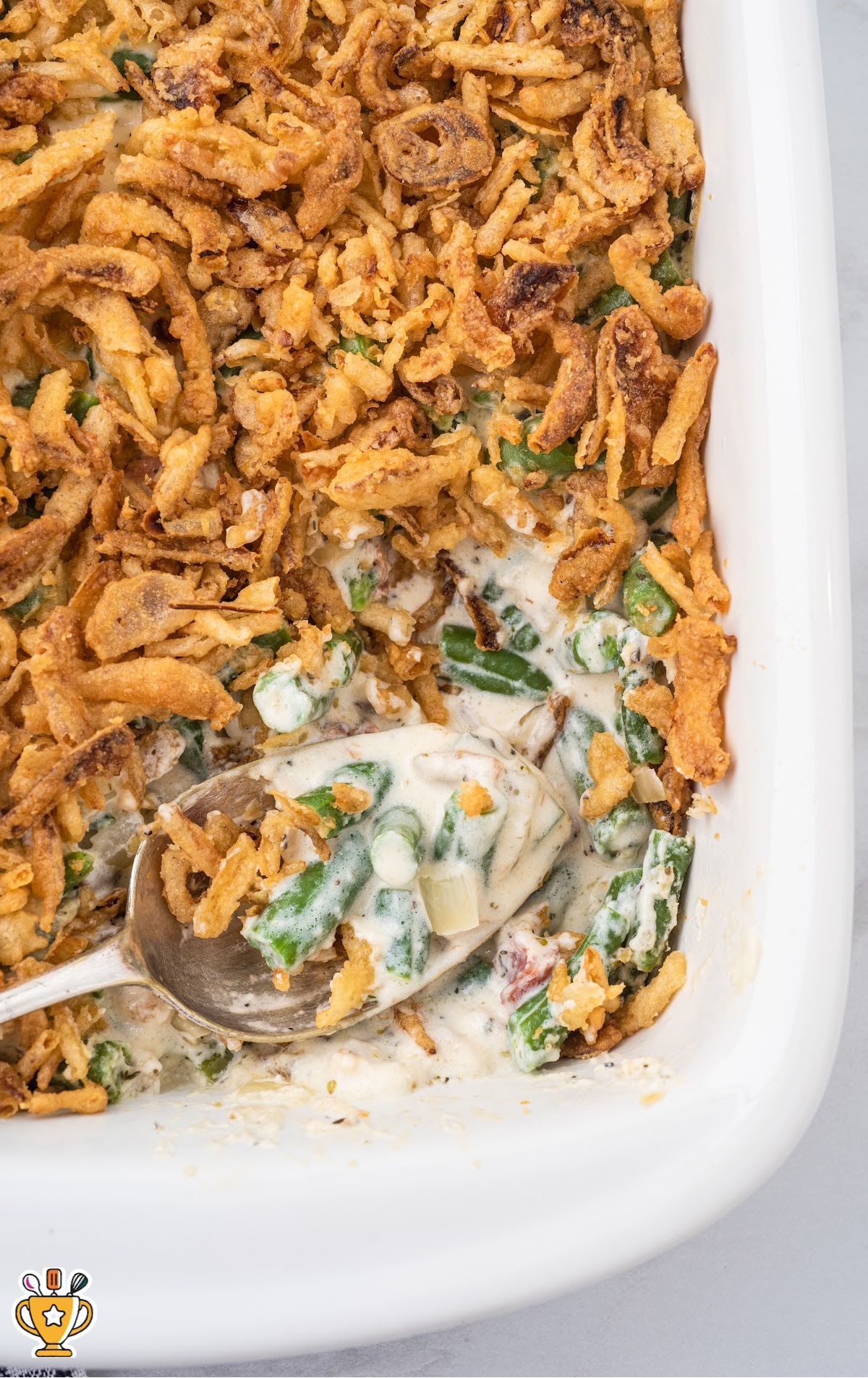 Green Bean Casserole in a white baking tray with a spoon