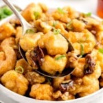 a serving dish of honey wanut shrimp with a large serving spoon