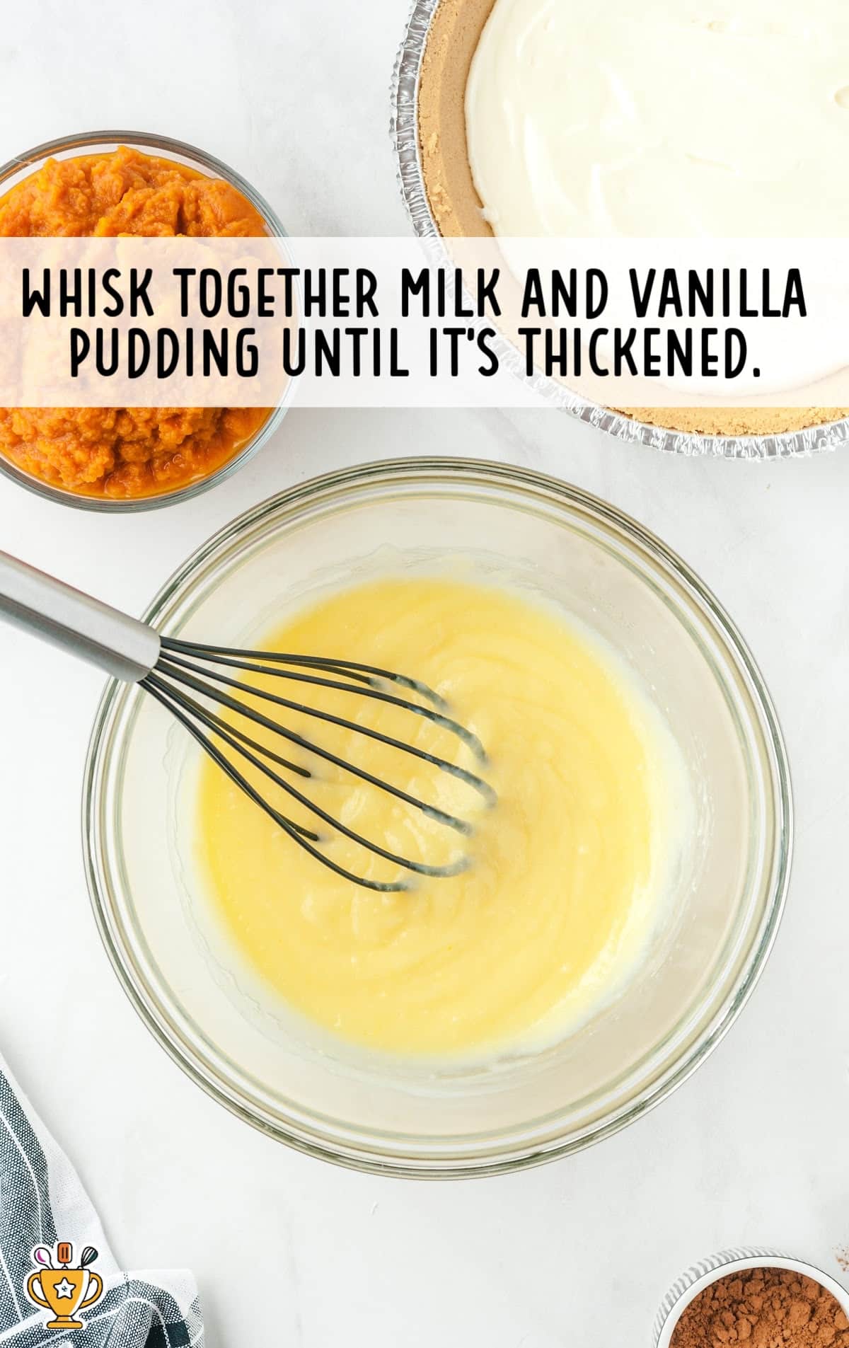 Milk and vanilla pudding mixed together in a bowl with a whisker