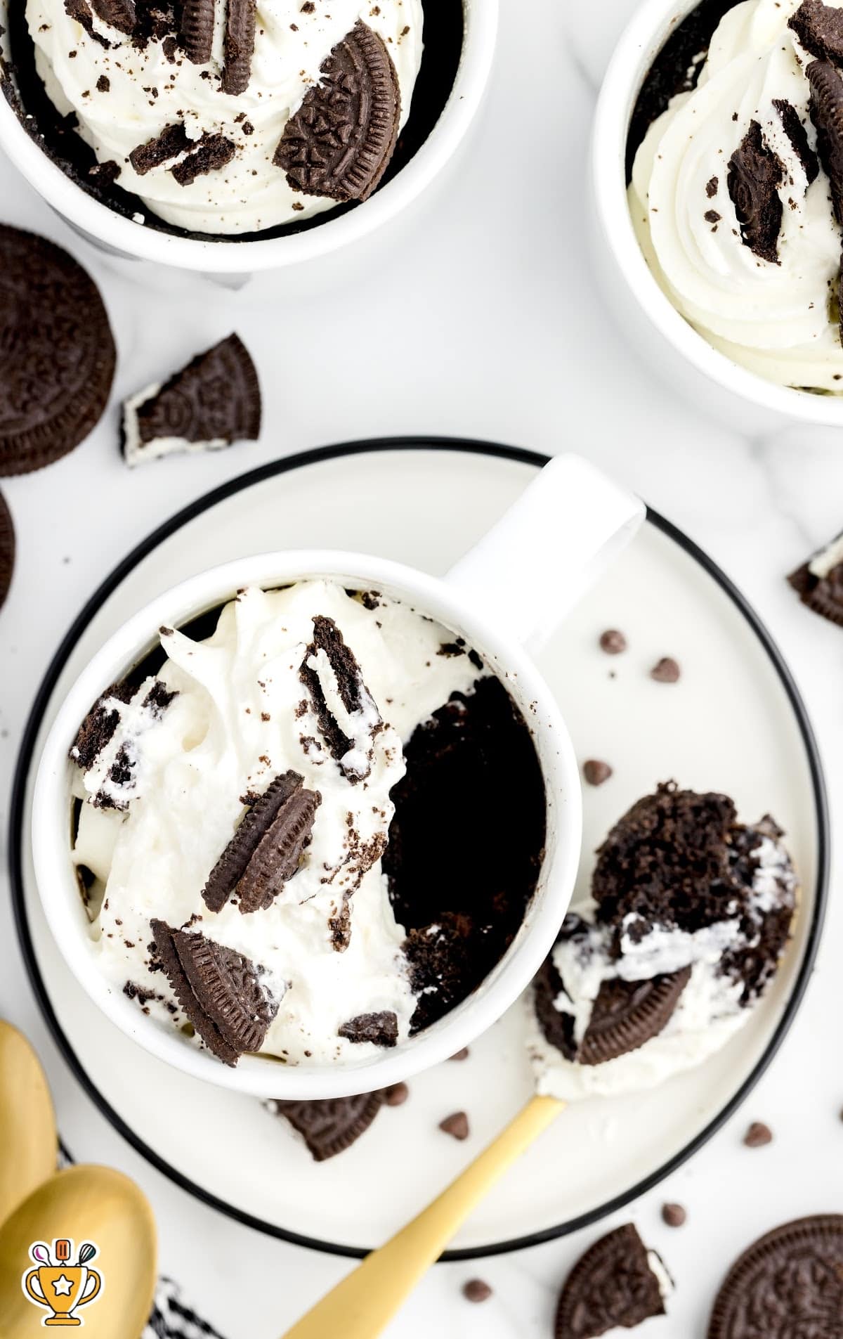 Oreo Mug Cake in a mug put on a plate with a scoop of cake on a wooden spoon