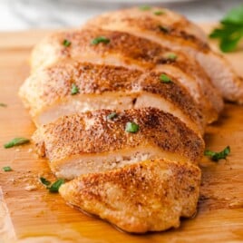 a piece of baked chicken on a cutting board, sliced.