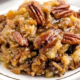 a white dessert plate with a serving of pecan dump cake.