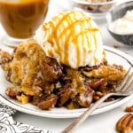 a scoop of pecan cake on a white plate with ice cream and caramel sauce on top.