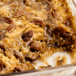Close-up of freshly baked pecan dump cake with a golden, gooey texture, crunchy pecans, and a rich caramelized layer in a glass baking dish.