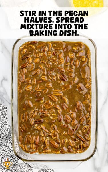 Glass baking dish filled with unbaked pecan dump cake mixture, showing a brown sugar, butter, and pecan filling spread evenly before baking.