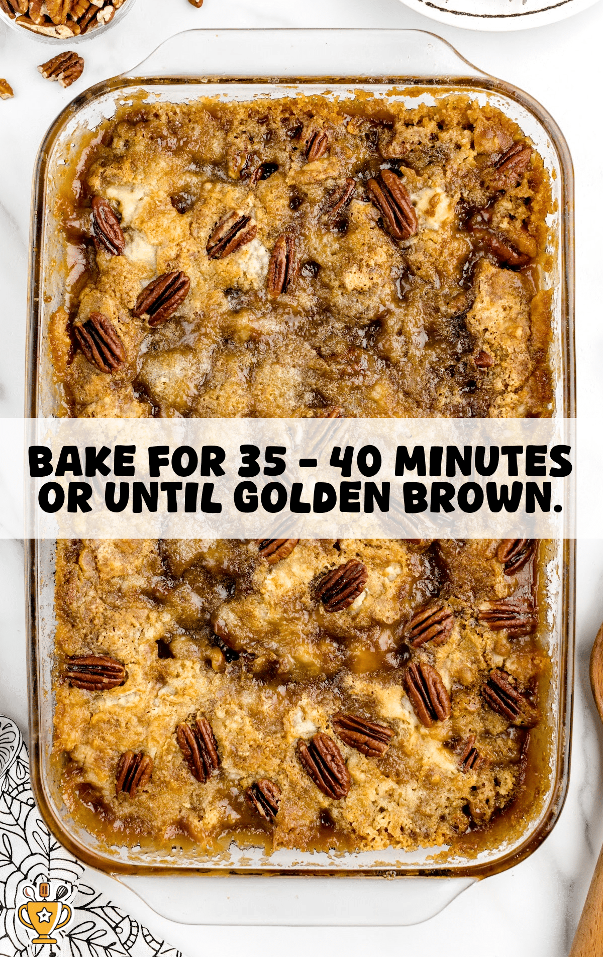 A freshly baked pecan dump cake in a glass dish, golden brown with bubbling caramelized edges and toasted pecans on top, ready to serve.