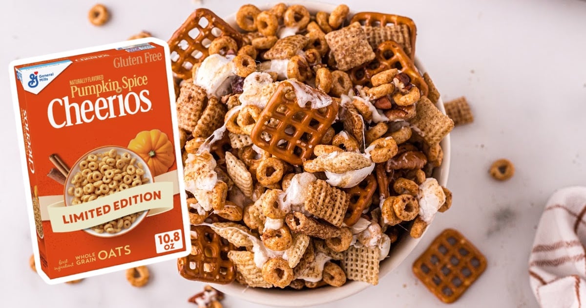 An aerial photo of a white bowl full of Pumpkin Spice Chex Mix, with a box of pumpkin spice cheerios