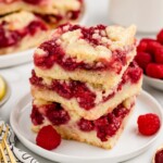 A stack of raspberry squares cut on a plate.