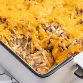 A white casserole dish of cooked hamburger hash browns.