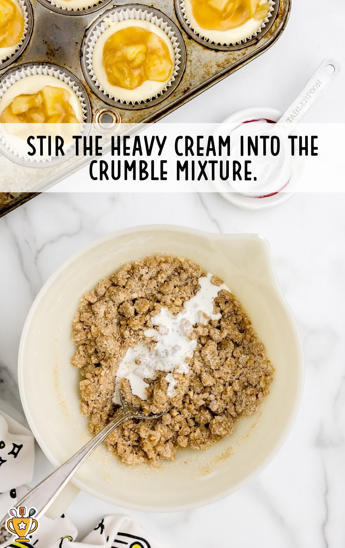 A white bowl containing crumble mixture , heavy cream with a spoon in it