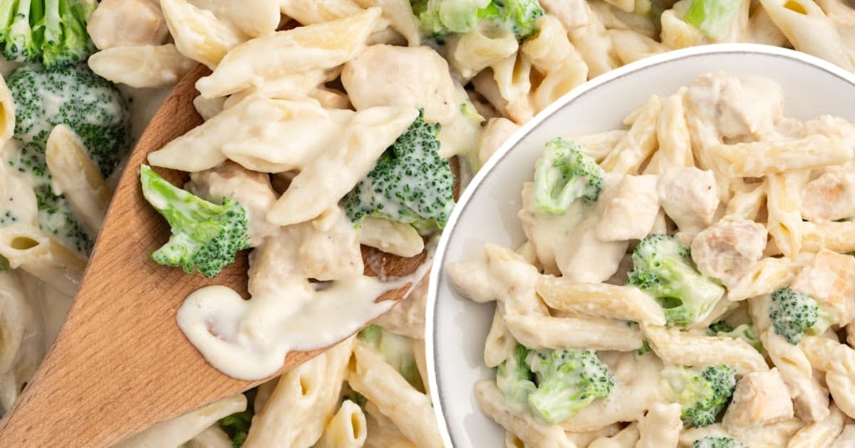 a plate of chicken broccoli alfredo with a wooden spoon.