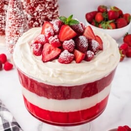 A trifle bowl of Christmas Trifle garnished with whipped cream and berries.