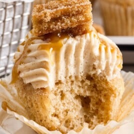 a churro cupcake with a bite out of it.