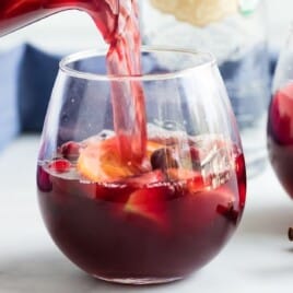 Fall Sangria being poured in a glass with some cinnamon bark on the side