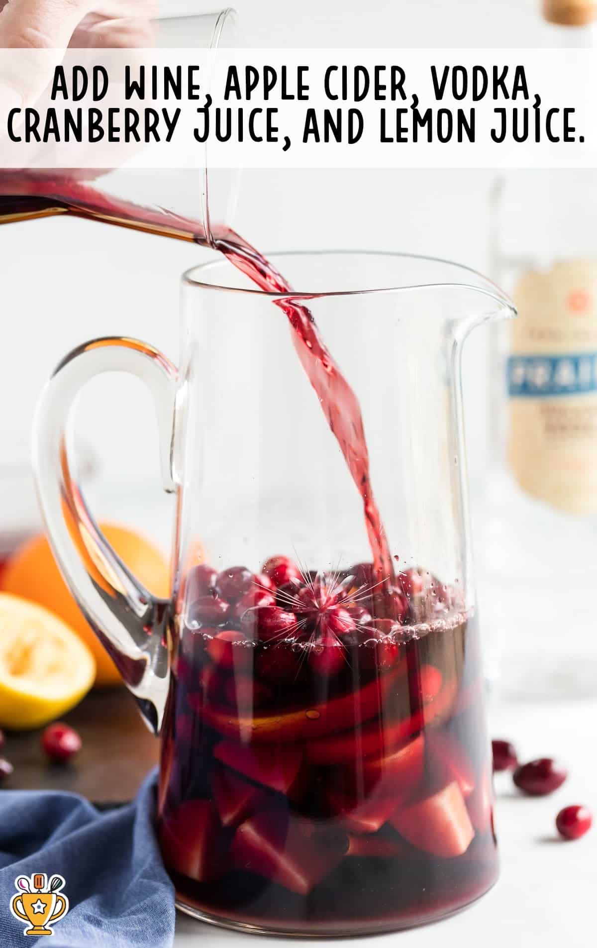 wine, apple cider, vodka, cranberry juice and lemon juice being added in a jar