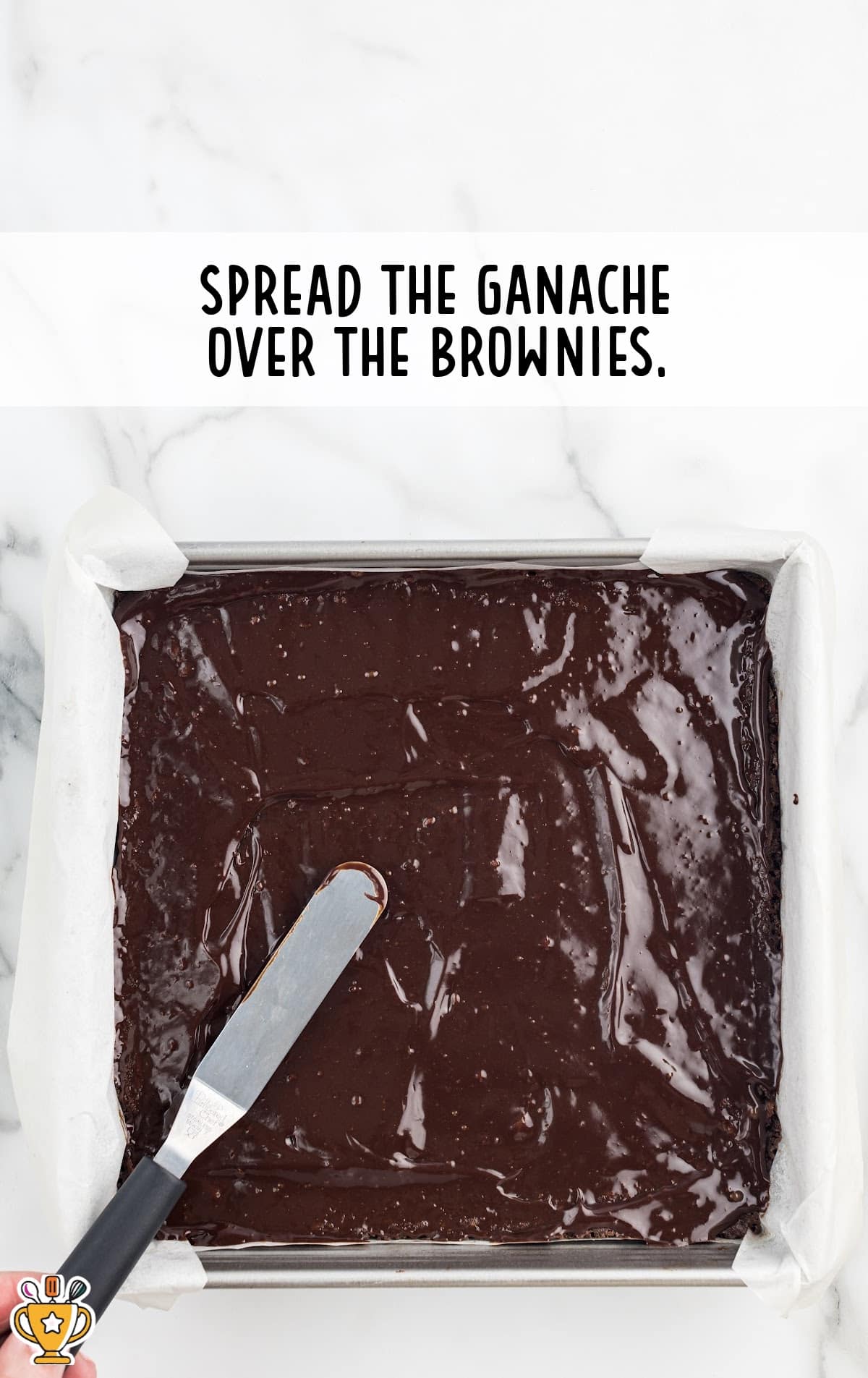 ganache spread over the brownies, with a spatula