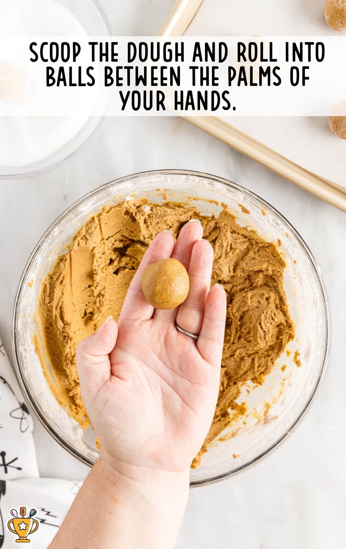 a hand holding a ball of Molasses Cookies and a bowl of Molasses Cookies dough under a hand