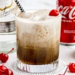 A coca cola paralyzer drink garnished with a cherry.