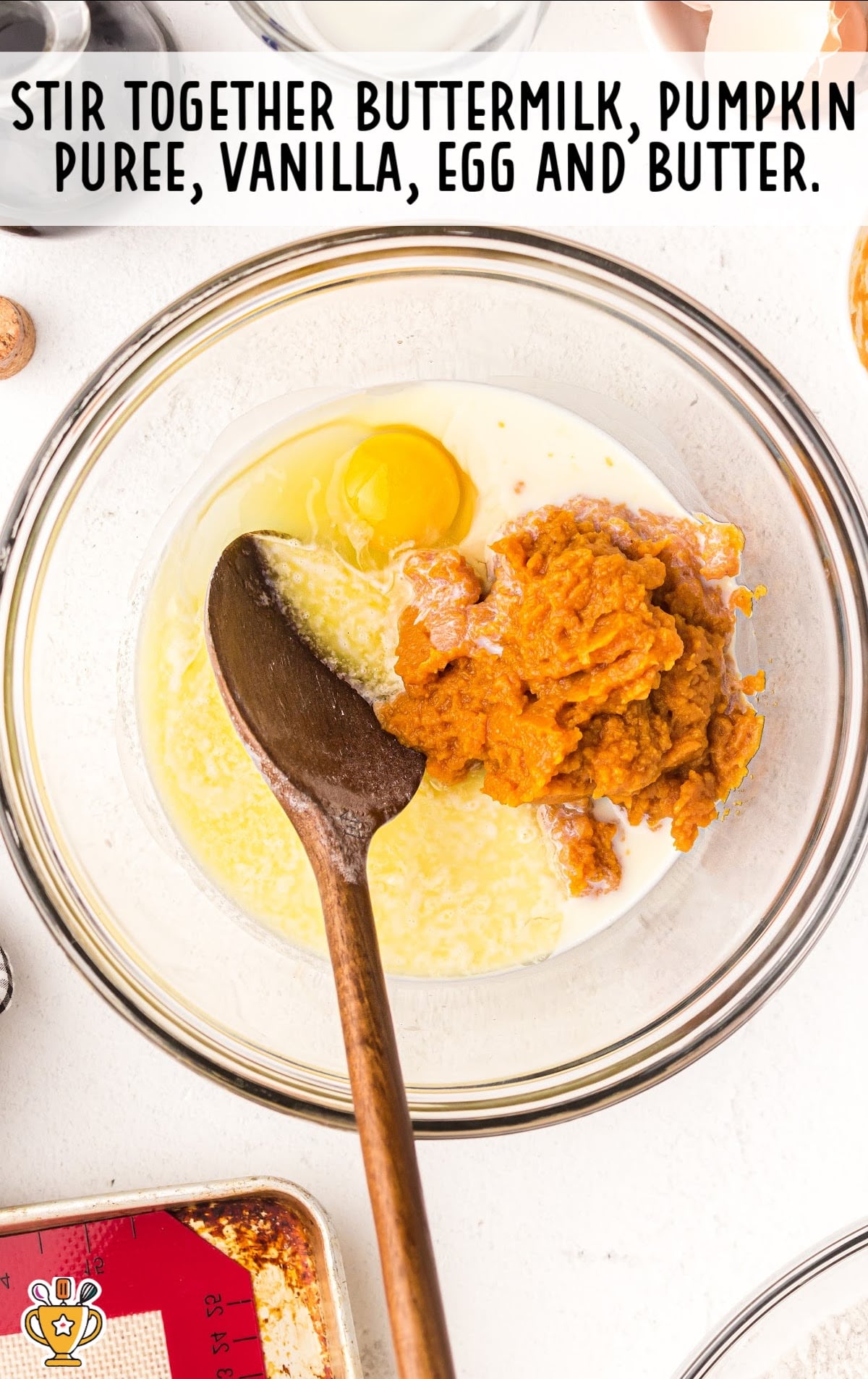 buttermilk, pumpkin puree, vanilla, egg and butter mixed in a clear bowl with a wooden spoon