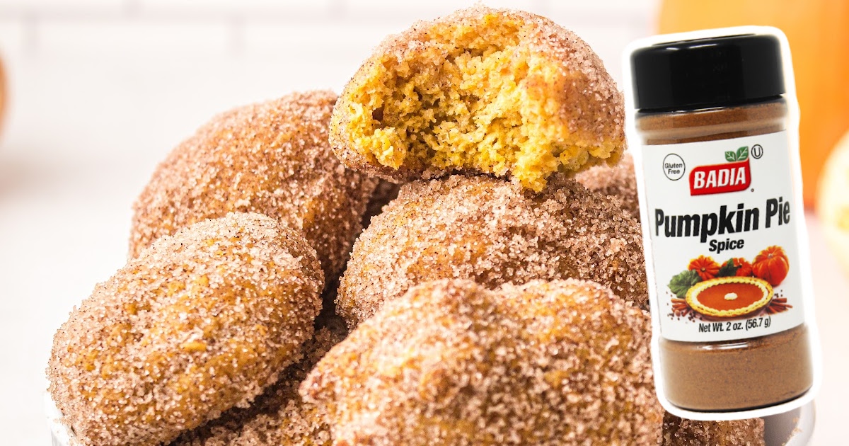 Pumpkin Donut Holes stacked together, one with a bite on it and a pumpkin pie jar on the side