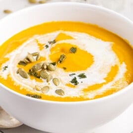 Pumpkin Soup in a bowl which is over a plate and spoon beside it