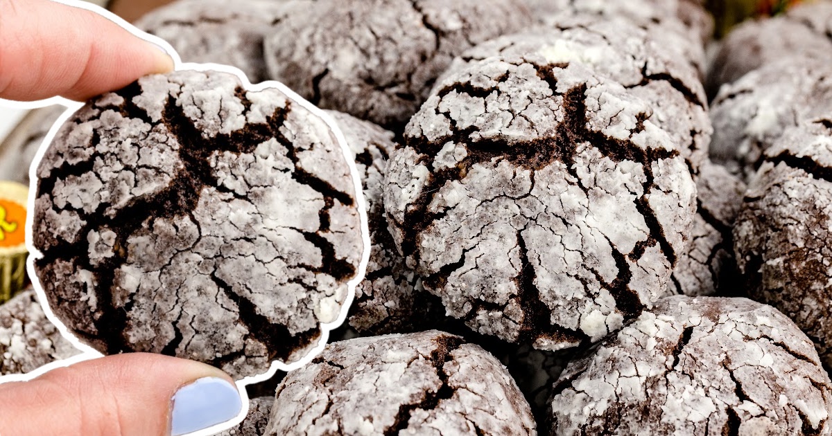 A hand holding a Reese's Crinkle Cookie and a bunch of Reese's Crinkle Cookies behind