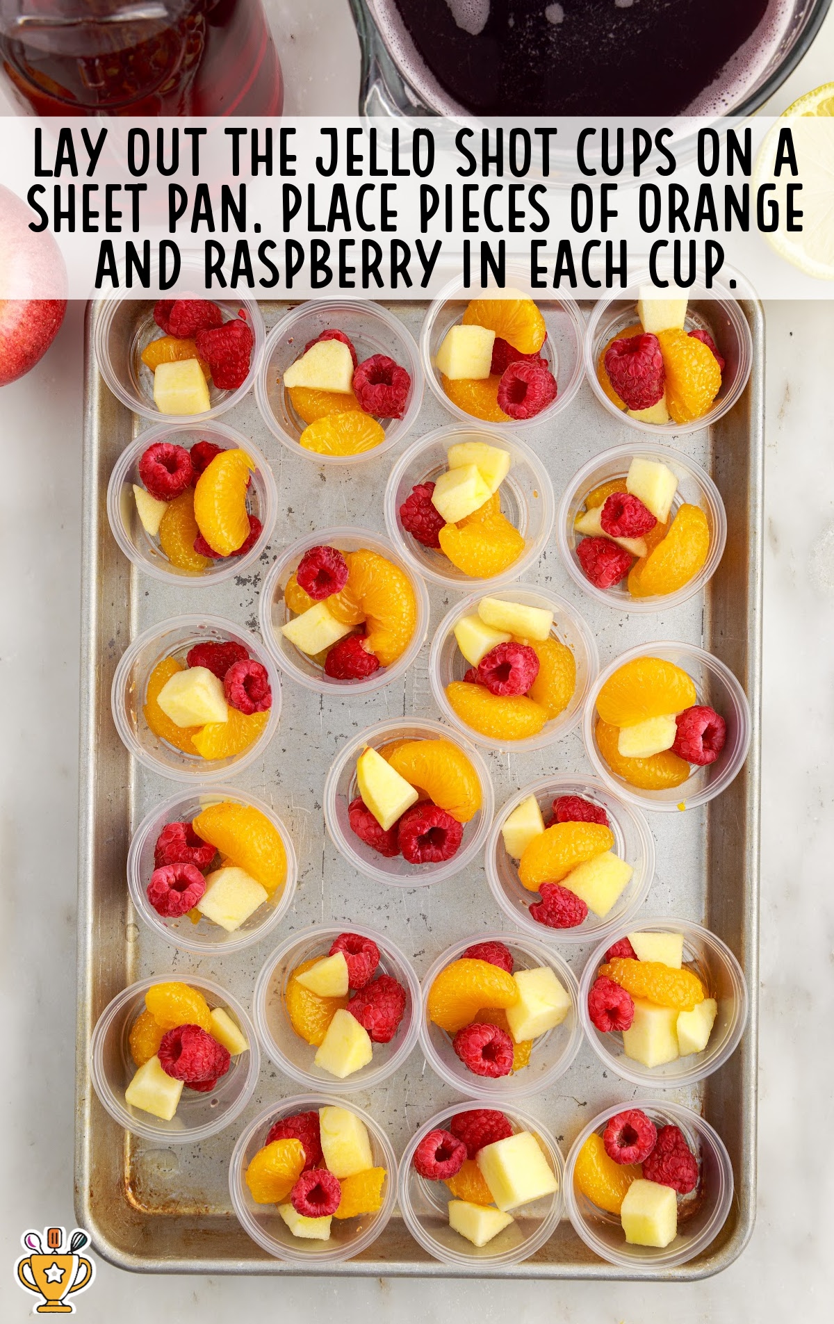 Sangria Jello Shot cups on a sheet pan with pieces of orange and raspberry inside