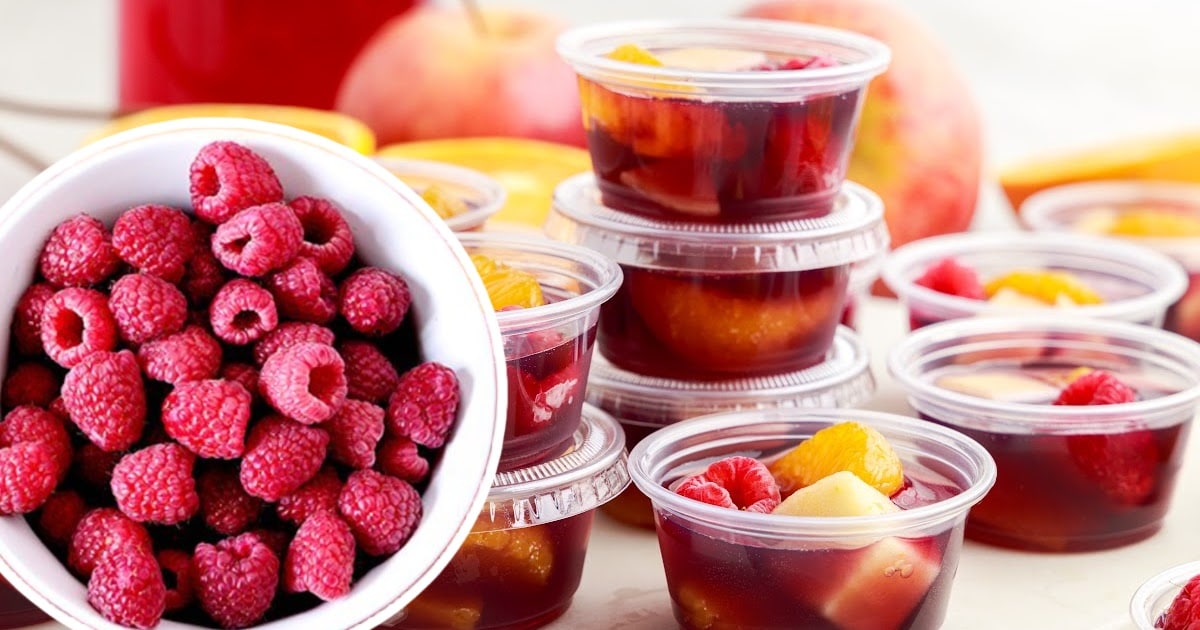 Cups of Sangria Jello Shots, with raspberries on the side