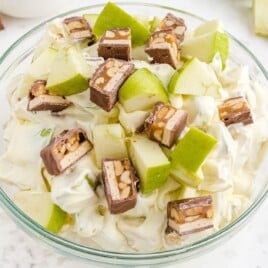 Snickers Salad in a bowl with a wooden spoon on the side
