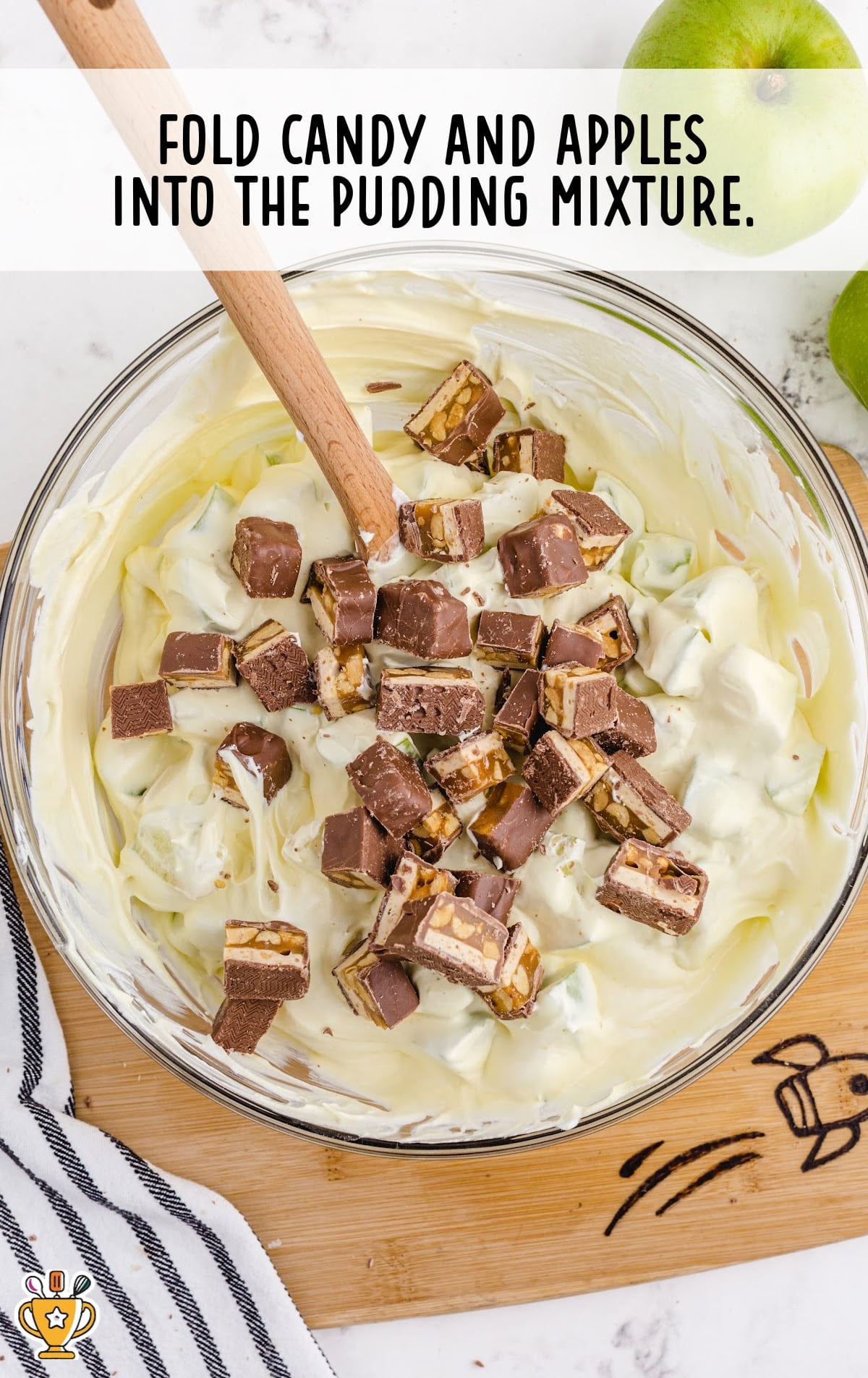 Candy and apples mixed with pudding mixture in a bowl