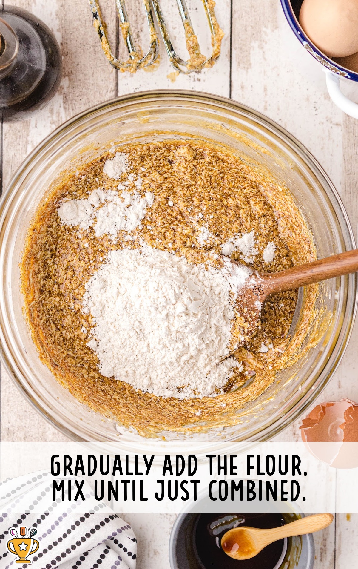 flour added into a bowl with a wooden spoon in it