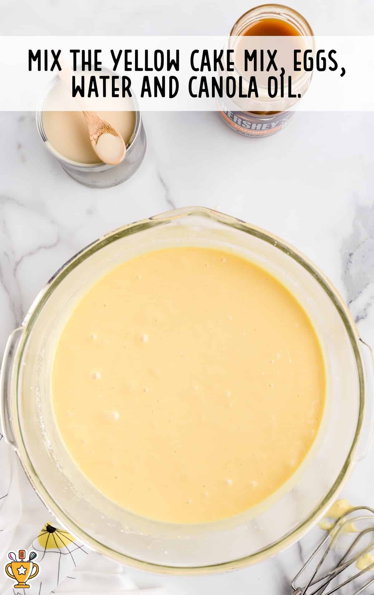A mixture of yellow cake mix, eggs, water and canola oil in a bowl